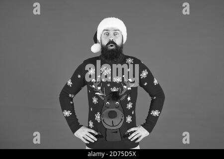 Hipster bärtiger Mann tragen winter Pullover und Hut mit roten Hintergrund. Holly Jolly Christmas. Frohes neues Jahr. Melden Sie Holiday Party. Winter party Outfit. Einladung hässliche Pullover Party. Pullover mit Rotwild. Stockfoto