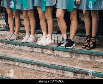 Dünne Mädchen Beine in blau kurze Röcke shod in verschiedenen Schuhe stehen auf den Stufen zusammen Stockfoto