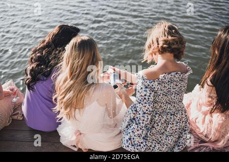 Mädchen in Kleidern auf einer Junggesellinnenparty trinken Rotwein Von Brillen Stockfoto