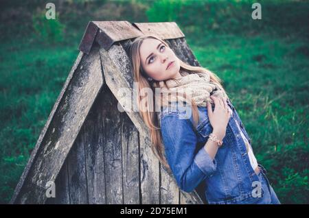 Blonde junge europäische Frau in blauem Denim Anzug und gestrickt Schal im Freien Stockfoto