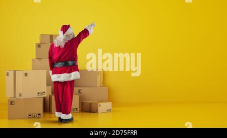 Weihnachtsmann vor Pappkartons, die etwas zeigen In der Wand Stockfoto