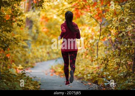 Herbstlauf aktiv fit Läufer Frau Joggen in Laubwald Wälder des Parks, gesund leben Lebensstil Cardio-Training an der frischen Luft im Freien Stockfoto