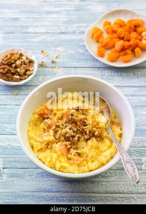 Maisbrei mit Kürbis, Honig und Walnüssen auf blauem Holzhintergrund Stockfoto