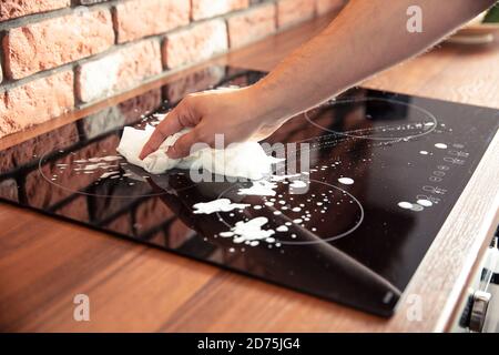 Man Hand Reinigung eines Induktionskochers mit etwas Reinigungsmittel Stockfoto