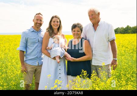 Glückliche Großeltern mit kleinen Baby Enkelin genießen Moment in schön Gelbes Feld mit dem übergeordneten Feld Stockfoto