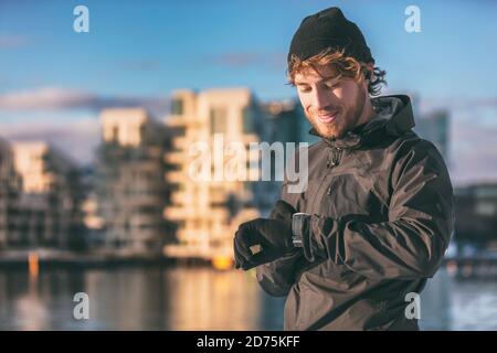 Smartwatch Runner Athlet Mann mit Blick auf seine tragbare Technologie smart Beobachten Sie beim morgendlichen Außenlauf, wie er seine Herzfrequenzdaten überprüft Lauftraining Stockfoto