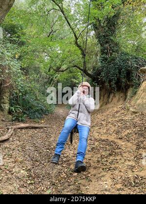 Frau schwingt auf einer Seilschaukel, die hohl an einem Baum hängt, East Chinnock, Somerset, England Stockfoto