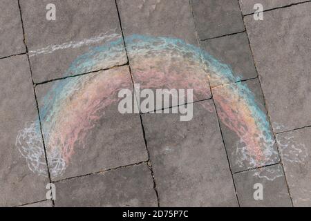 Ein Regenbogen gezeichnet mit Buntstiften auf der Straße. Regenbogen-LGBT-Symbol auf dem Asphalt. Die Kreativität der Kinder im Hof. Regenbogen gezeichnet mit Bürgersteig Stockfoto