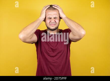 Russischer Mann trägt einfaches rotes T-Shirt über gelbem, insolierten Hintergrund Leiden unter Kopfschmerzen verzweifelt und gestresst, weil Schmerzen und Migräne Mit h Stockfoto
