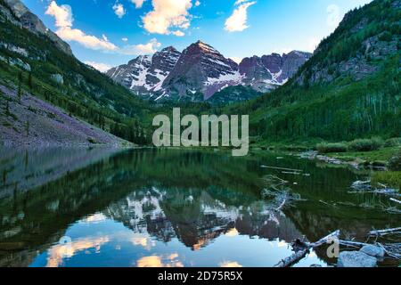Maroon Bells in Aspen Colorado at Sunset. Beautiful maroon colors and pink clouds reflecting off glassy water. Reflection of mountain tops on water fr Stockfoto