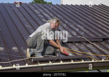 Reparatur des Daches des Hauses mit Schrauben Antrieb Werkzeuge. Arbeiter Dachdecker Baumeister arbeiten auf Dachkonstruktion Stockfoto