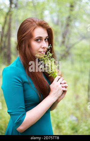 Schöne Frau im Wald Kleid hält Blumen in den Händen. Stockfoto