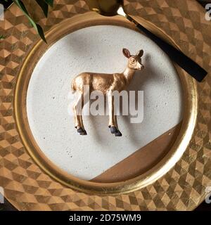 Urlaubsort Einstellung und Spielzeug golden Rentier Dekoration auf dem Teller durch die natürlichen Zweige umgeben, auf Holz- Hintergrund. Stockfoto