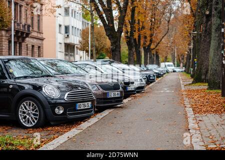 Straßburg, Frankreich - 18. Oktober 2020: Reihe von mehreren Autos auf öffentlichen Parkplätzen in Reihe Autos und Radweg in Herbst Stadt Straßburg geparkt Stockfoto