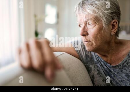 Portrait der älteren Frau auf Sofa, die unter Depressionen leiden Stockfoto