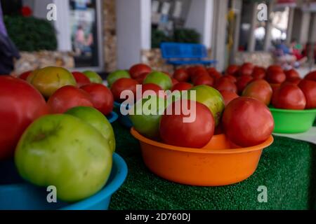 Plastikschüsseln gefüllt mit frischen reifen und unreifen Tomaten auf einem Tisch auf einem Bauernmarkt. Stockfoto