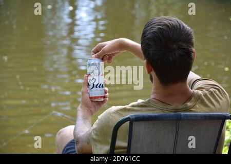 KHARKOV, UKRAINE - AUGUST 22 2020: Man hält Budweiser Lager Alkoholbier während des Fischens. Budweiser ist Marke von Anheuser-Busch Inbev am beliebtesten in Stockfoto