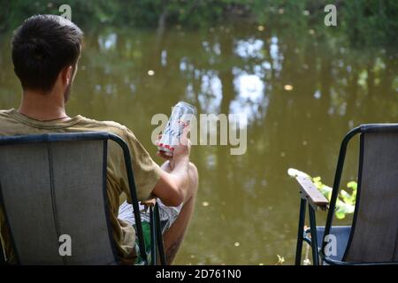 KHARKOV, UKRAINE - AUGUST 22 2020: Man hält Budweiser Lager Alkoholbier während des Fischens. Budweiser ist Marke von Anheuser-Busch Inbev am beliebtesten in Stockfoto