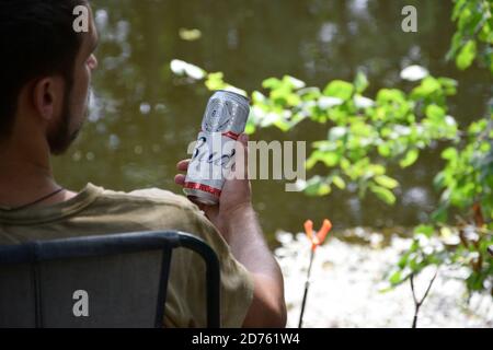 KHARKOV, UKRAINE - AUGUST 22 2020: Man hält Budweiser Lager Alkoholbier während des Fischens. Budweiser ist Marke von Anheuser-Busch Inbev am beliebtesten in Stockfoto