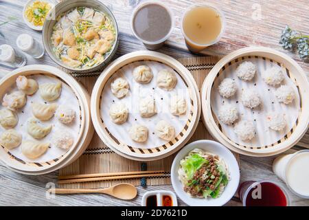 Gedämpfte Xiaolongbao und gedünstete Knödel in einem traditionellen Dampfgaren serviert Korb (Nahaufnahme) Stockfoto