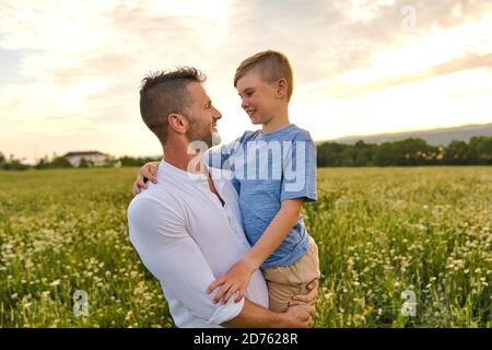 Die glückliche Familie des Vaters und des Kindes auf dem Feld bei der Sonnenuntergang Spaß haben Stockfoto