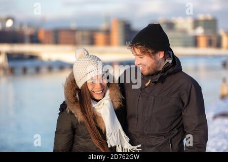 Happy Winter Freunde Paar lachen zusammen Spaziergang in der Stadt im Freien tragen kaltes Wetter Accessoires, Hüte, Jacken, Schal. Asiatische Mädchen nehmen mit Stockfoto
