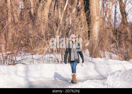 Winterspaziergang glückliche Frau beim Spaziergang im Schnee Outdoor Naturpark genießen sonnigen Tag tragen Sonnenbrille. Junge aktive Person auf einem Spaziergang im Wald Stockfoto