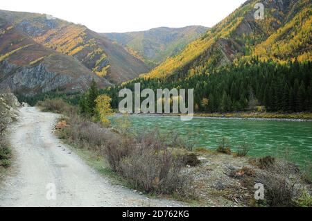 Ein Bergpfad entlang der felsigen Steigung des Berges, parallel zur turbulenten Strömung des türkisfarbenen Flusses. Katun, Altai, Sibirien, Russland. Stockfoto