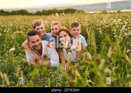 Glückliche Familie auf Gänseblümchen Feld bei Sonnenuntergang mit großen Zeit zusammen Stockfoto