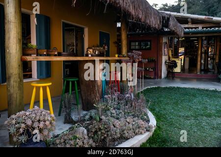 Eine Arbeitsplatte unter einem Strohdach wunderschön mit Vintage-Objekten im Garten des Moara Cafe in Cunha, Sao Paulo - Brasilien dekoriert. Stockfoto