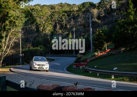 Ein weißer Fiat Linea, der an einem S-förmigen Abschnitt der Salvador Pacetti Straße vorbeifährt, direkt vor dem Moara Cafe am späten Nachmittag. Stockfoto