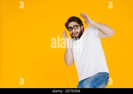 Porträt eines zotteligen, bärtigen, verängstigten Mannes in 3D-Brille mit offenem Mund und großen Augen, auf gelbem Hintergrund. Stockfoto