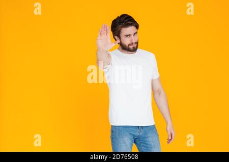 Ein verärgerter ernster junger bärtiger Mann in seinen 30ern Ein weißes T-Shirt zeigt eine Stop-Geste mit dem Handfläche mit Blick auf die Kamera Stockfoto