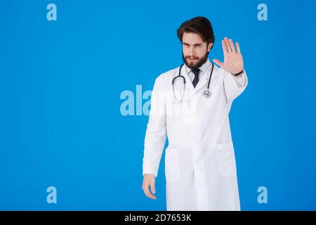 Porträt eines seriösen Arztes in professionellen medizinischen weißen Mantel zeigt Ablehnung Geste von Anschlag Handfläche Zeichen. DOC man isoliert auf blauem Hintergrund. Stockfoto
