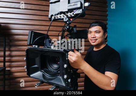 Asiatischer Fotograf mit einer Filmkamera im Drehset. Stockfoto