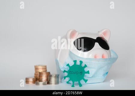 Der Zusammenbruch der Finanzmärkte und die Gefahr für finanzielle Ersparnisse aufgrund eines Pandemie-Virus.Masked Sparschwein Stockfoto