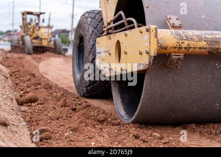 Nahaufnahme Gelber Vibrationsboden und Motorgrader Zivilverdichter Arbeiten auf der Baustelle, Gelber Vibrationsboden Verdichter in der Straße constructio Stockfoto