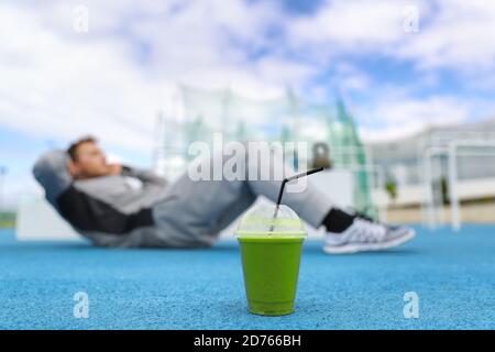 Fitness-Mann Training im Fitnessstudio mit grünem Smoothie Detox Drink Tun Sit-ups Übungen auf dem Boden im Freien Stockfoto