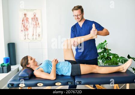 Männlicher physischer Therapeut, der einen weiblichen Patienten dehnt Stockfoto