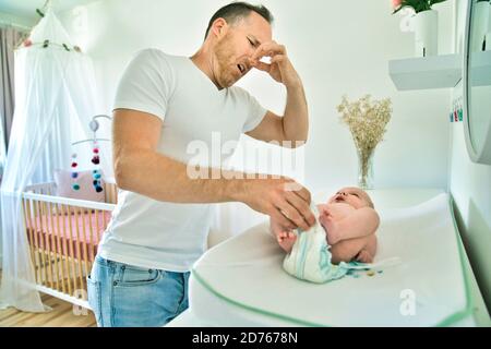 A Father Changing Baby's Winper in Kinderzimmer Stockfoto