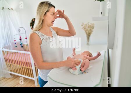 Eine Mutter, die die Wickelwindel im Kinderzimmer wechselt Stockfoto