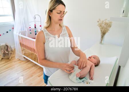 Eine Mutter, die die Wickelwindel im Kinderzimmer wechselt Stockfoto