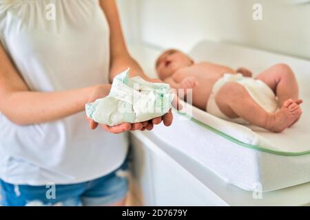 Eine Mutter, die die Wickelwindel im Kinderzimmer mit der Windel hält Stockfoto