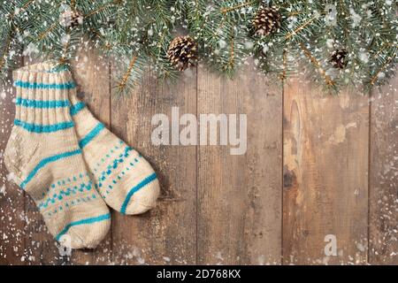 Hintergrund mit Tannenzweigen und einer Reihe von Weihnachtsdekorationen auf einem dunklen Holzhintergrund. Wollsocken, Tannenzweige, Zapfen und Schneeflocken, auf rau Stockfoto
