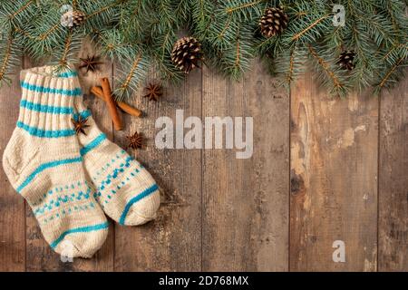 Vintage Weihnachten Hintergrund. Rustikaler Holzhintergrund mit Tannenzweigen, Zapfen, Zimtstangen, Anis, Wollsocken. Platz kopieren. Draufsicht Stockfoto