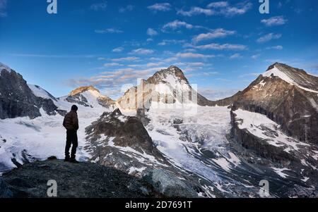 Männlicher Tourist begrüßt neuen Tag in den Schweizer Alpen, Morgen helle Sonne scheint auf den Gipfeln, Dent Blanche, während Tal ist noch im Schatten Stockfoto