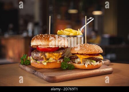 Zwei Stück Hamburger mit Pommes auf Holzschnitt serviert Platine Stockfoto