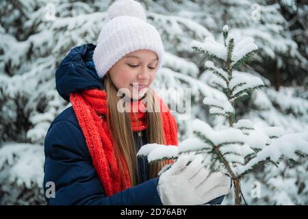 Eine schöne Schülerin verbringt ihre Ferien in einem Landhaus und spaziert durch einen Winterwald mit Tannen, Kiefern und Schnee Stockfoto
