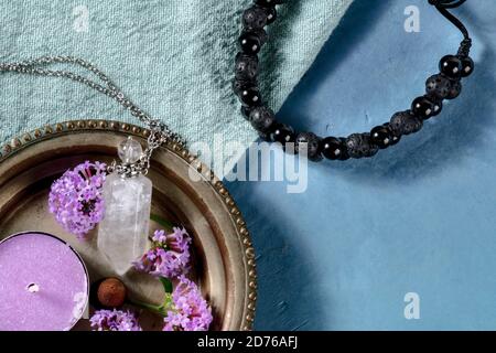 Aromatherapie-Konzept. Lava Armband, Parfüm Fläschchen, Duftkerze, vervain Blumen, von oben mit einem Platz für Text auf blauem Hintergrund geschossen Stockfoto