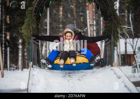 Die Eltern kauften ihre Kinder Tubing und nun fährt die ganze Familie die Eisrutsche hinunter. Stockfoto